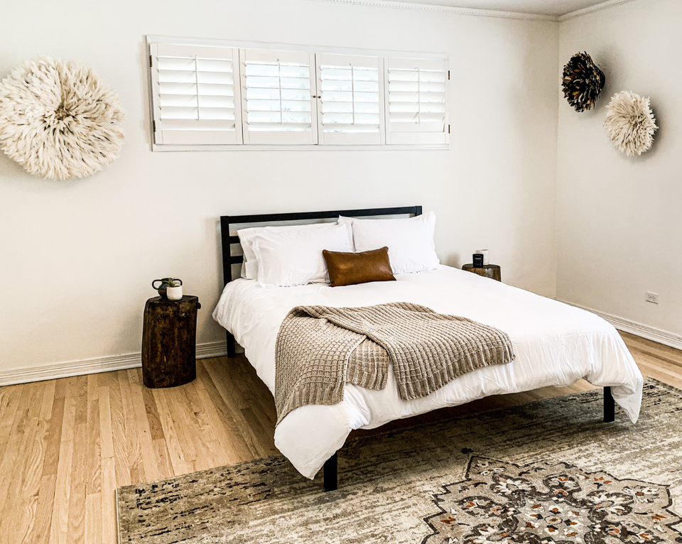 <img src="neutralbedroomwithstumpsidetable_projects.png" alt="White bedroom with light wood floors and bed made with white bedding, leather throw pillow, and stump side table">