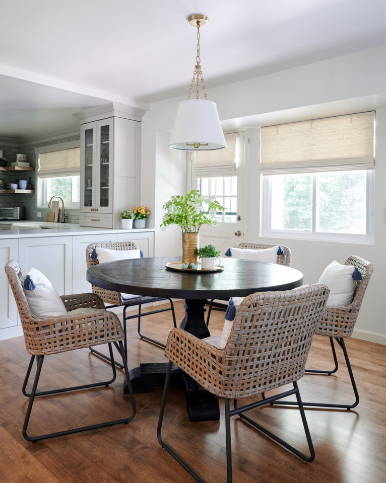 <img src="roundblackdiningtablewithwovenchairs.png" alt="Dining room designed by Amy Rogala featuring a round black dining table, tan woven dining chairs, white pendant light, and flowers as center piece">